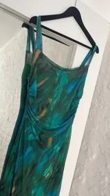 Vestido largo ajustado al cuerpo, confeccionado en microtul estampado con diseño abstracto en tonos verde, azul y marrón. Tiene breteles finos y forro interior opaco.