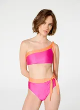 Bikini de dos piezas marca Blueman, con corpiño asimétrico de un solo hombro y bombacha de tiro alto con lazos laterales. Diseño color fucsia con detalles en naranja.