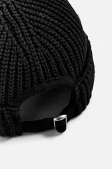Gorro negro corto de punto con ajuste con trabilla y acabado con vuelta.
