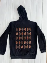 Hoodie gris oscuro con capucha y cordones ajustables. Estampado en la espalda con diseño de hojas en tonos naranja y beige.