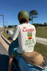 Remera manga corta oversize color crudo con estampa en la espalda que incluye el texto "Essenza Rosso Italiano", una lata de jugo de tomate y la leyenda "Open al day serving pizza".