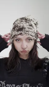 Gorro de lana marrón y beige con diseño de líneas sueltas.