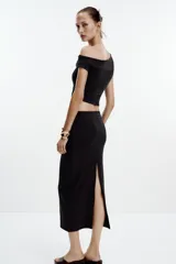 Falda midi color crema, de tiro alto con cintura elástica y detalle de pliegues laterales.