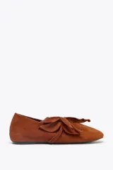 Zapato plano tipo bailarina color marrón de cuero gamuzado, con detalle de flor fantasía en la parte delantera y punta redonda.
