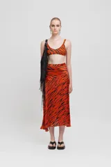 Falda tubo midi color naranja con estampado animal en negro, cremallera lateral invisible, detalle de peplum moldeado y bajo ligeramente acampanado.