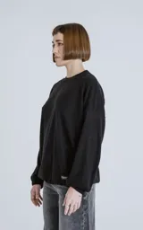 Sweater negro de corte holgado con cuello redondo y mangas largas con puños ajustados.