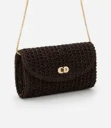 Cartera pequeña tipo bandolera confeccionada en rafia color marrón con textura tejida. Cuenta con una correa de cadena dorada y cierre de broche metálico en el frente.