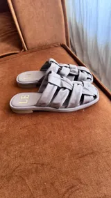 Sandalias bajas color rosa viejo con tiras de cuero entrelazadas y suela marrón.