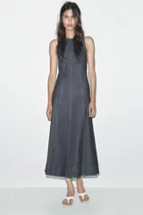 Vestido midi de denim azul oscuro, con cuello redondo y sin mangas. Presenta costuras a contraste y cierre trasero con cremallera oculta.