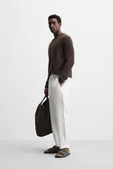 Pantalón de lino color marrón oscuro, de corte recto y relaxed fit. Tiene cintura elástica ajustable con cordón, bolsillos frontales y traseros de parche.