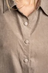 Camisa color marrón claro de gamuza vegana con calce oversize, cuello clásico, cierre frontal con botones y mangas largas con puños abotonados.