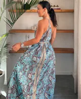 Vestido largo tipo solera, color turquesa con estampado paisley en tonos marrones y dorados. Diseño con escote halter anudado al cuello y abertura frontal central en color liso.