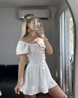 Vestido corto blanco con escote off-shoulder, mangas cortas abullonadas y cintura elastizada.