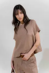 Blusa de lino color beige con rayas verticales negras, corte recto, escote redondo y mangas cortas.