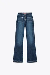 Pantalón de jean azul oscuro, de tiro alto y corte bootcut. Presenta bolsillos de parche delanteros y traseros, cierre frontal con botones y ruedo sin costuras.