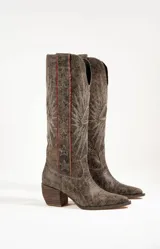 Botas texanas de cuero color marrón con bordados de estrellas y rayos de sol en color blanco. Presentan detalles en rojo en los bordes superiores y un taco de madera. El largo de la caña es de 42cm y la circunferencia de 37cm.