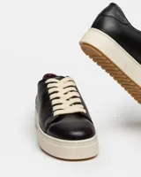 Sneaker de cuero liso en color blanco, con suela gruesa y cordones al tono.