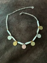 Collar corto con perlas de río naturales, cuentas metálicas de acero quirúrgico, medallitas bañadas en plata y oro y mostacillas. Se cierra con cadena de acero quirúrgico y ganchito para regular el largo.