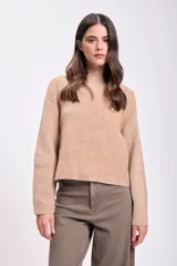 Sweater color beige de punto con cuello alto y mangas ranglan largas. Tejido acanalado vertical.