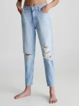 Jeans celeste claro de corte mom, con roturas en las rodillas, tiro alto, cinco bolsillos y cierre con botón y cremallera.