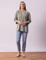 Blusa verde con rayas verticales blancas, cuello a la base y escote en V con aplique de botones. Manga ¾ con puño y botón. Tajo en costuras laterales.