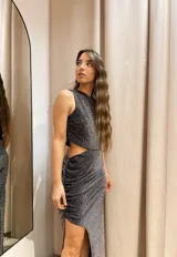 Vestido largo color dorado de lurex, con un hombro descubierto, corte en la cintura y falda con frunces y abertura lateral.