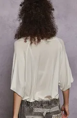 Remera manga corta color blanco hueso, de corte holgado y tejido liviano. Presenta cuello redondo y bolsillo de parche en el pecho.