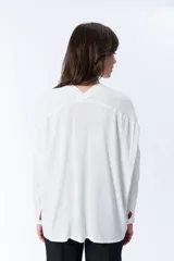 Blusa blanca de manga larga con escote en V y cierre frontal con botones.