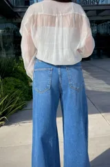 Camisa blanca traslúcida con botones y estampado de flores anaranjadas.