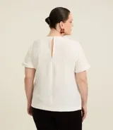 Blusa color beige de mangas cortas, cuello redondo con detalle de costuras y cierre trasero con botón.