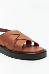 Sandalias negras de símil cuero con agarre ajustable en el talón y capellada entrelazada. Plataforma de 3 cm de alto.