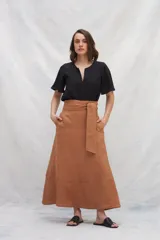 Falda midi color marrón de lino con bolsillos laterales y volante en el ruedo. Tiene una tira en la cintura para anudar en la delantera.