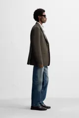 Blazer straight fit color marrón oscuro con finas rayas verticales claras. Confeccionado en tejido con lana de origen italiano. Cuello con solapas de muesca y manga larga acabada en puño con botones. Bolsillos de vivo en pecho y de solapa en cadera. Detalle de bolsillo interior. Bajo con aberturas en espalda. Cierre frontal de botonadura.