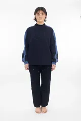 Buzo negro de algodón grueso con cuello alto y mangas largas con rayas blancas.