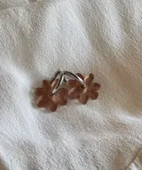 Aros colgantes dorados con forma de flor blanca.