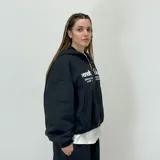 Campera negra con capucha y cierre frontal, corte boxy, con bolsillos laterales y estampado con el logo de la marca en color blanco.