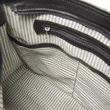 Cartera tipo hobo de cuero negro con diseño tejido y asa de hombro.