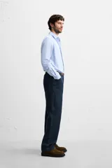 Camisa celeste de corte slim fit, confeccionada en tejido de algodón. Tiene cuello italiano, mangas largas con puños abotonados y cierre frontal con botones.