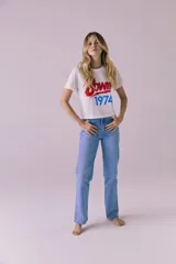 Remera blanca de manga corta con estampado frontal de la leyenda 'Bowie' en rojo y '1974' en azul.