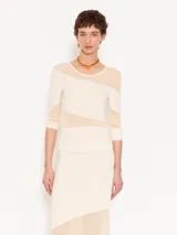 Top ajustado al cuerpo, largo hasta la primera cadera y mangas 3/4. Combina tejido liso color crema con organza transparente en diagonal.