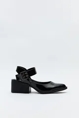 Zapato negro de charol con taco ancho y tira ancha con hebilla metálica.