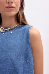 Musculosa de jean azul, sin mangas, con escote en V en la espalda que se cierra mediante dos lazos anudados.