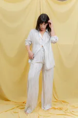 Conjunto color beige compuesto por una camisa oversize de manga larga con botones frontales y bolsillo en el pecho, y un pantalón amplio con cintura elástica.