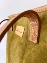 Bolso tipo tote de cuero color verde oliva con laterales de cuero texturizado color beige y manijas de cuero color marrón.