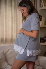Pijama maternal gris con remera de manga corta con botones a presión para amamantar y detalle de puntilla en el ruedo, y short con cintura ajustable.