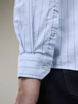 Camisa celeste a rayas verticales, de manga larga y corte clásico.