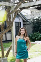 Vestido corto turquesa con escote halter y espalda descubierta. El cuello es alto y las tiras se atan en la nuca.