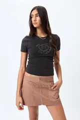 Minifalda color marrón claro, de corte recto con cierre metálico visible al frente y bolsillos decorativos con tachas.