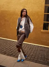 Chaleco de cuero marrón oscuro, estilo chaleco de trabajo o western, con cuello en V, cierre frontal y bolsillo con cremallera en el pecho.