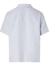 Camisa celeste de manga corta con cuello cubano, cierre frontal con botones y bolsillo de parche en el pecho.